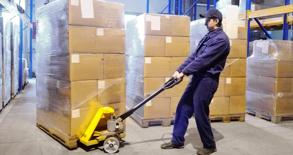 Opérateur logistique déplaçant une palette avec un transpalette dans un entrepôt